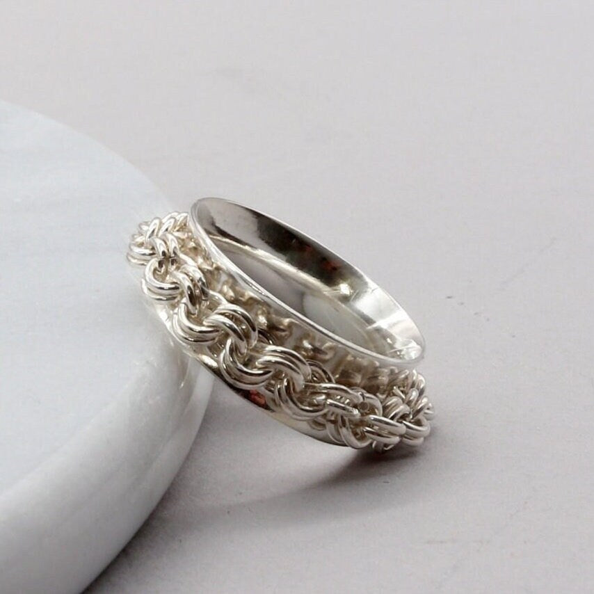 Closeup of detail on Rotating chain ring shown leaning on white marble.