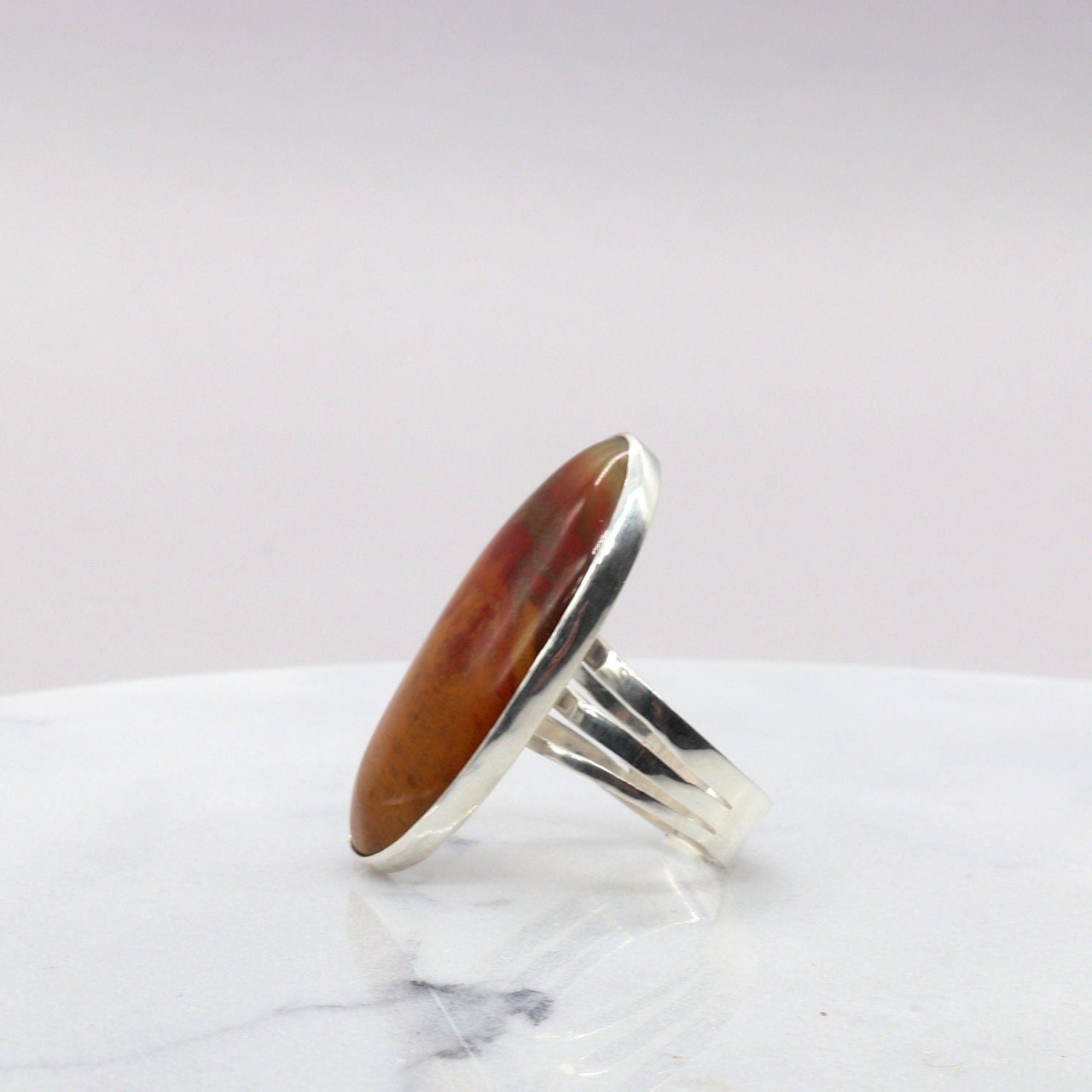 Side view of a vivid red orange and brown Sonoran Sunrise gemstone ring  set in a handcrafted band of Argentium® 935 Silver.