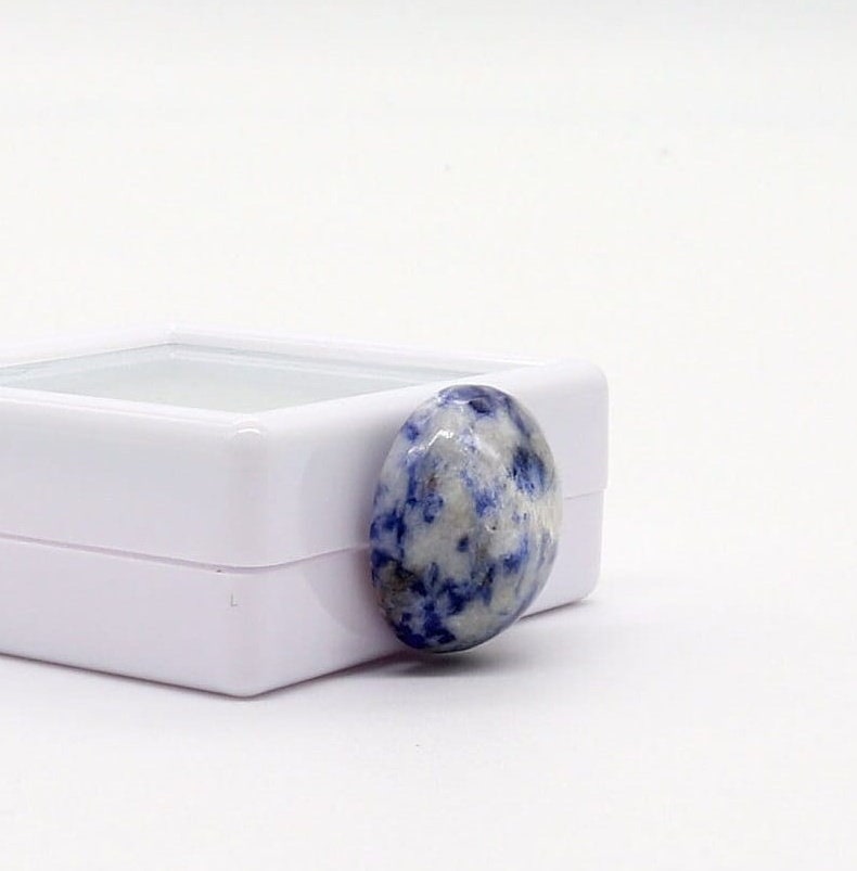 Blue Brazilian Sodalite Cabochon for Jewelry Making, Natural Gemstone, USA  The gemstone is displayed in a simple, white gem box display case with glass lid, for storage for gifting. The overall impression is one of elegance and natural beauty, highlighting the unique characteristics of this cabochon. This image showcases a high-quality, natura