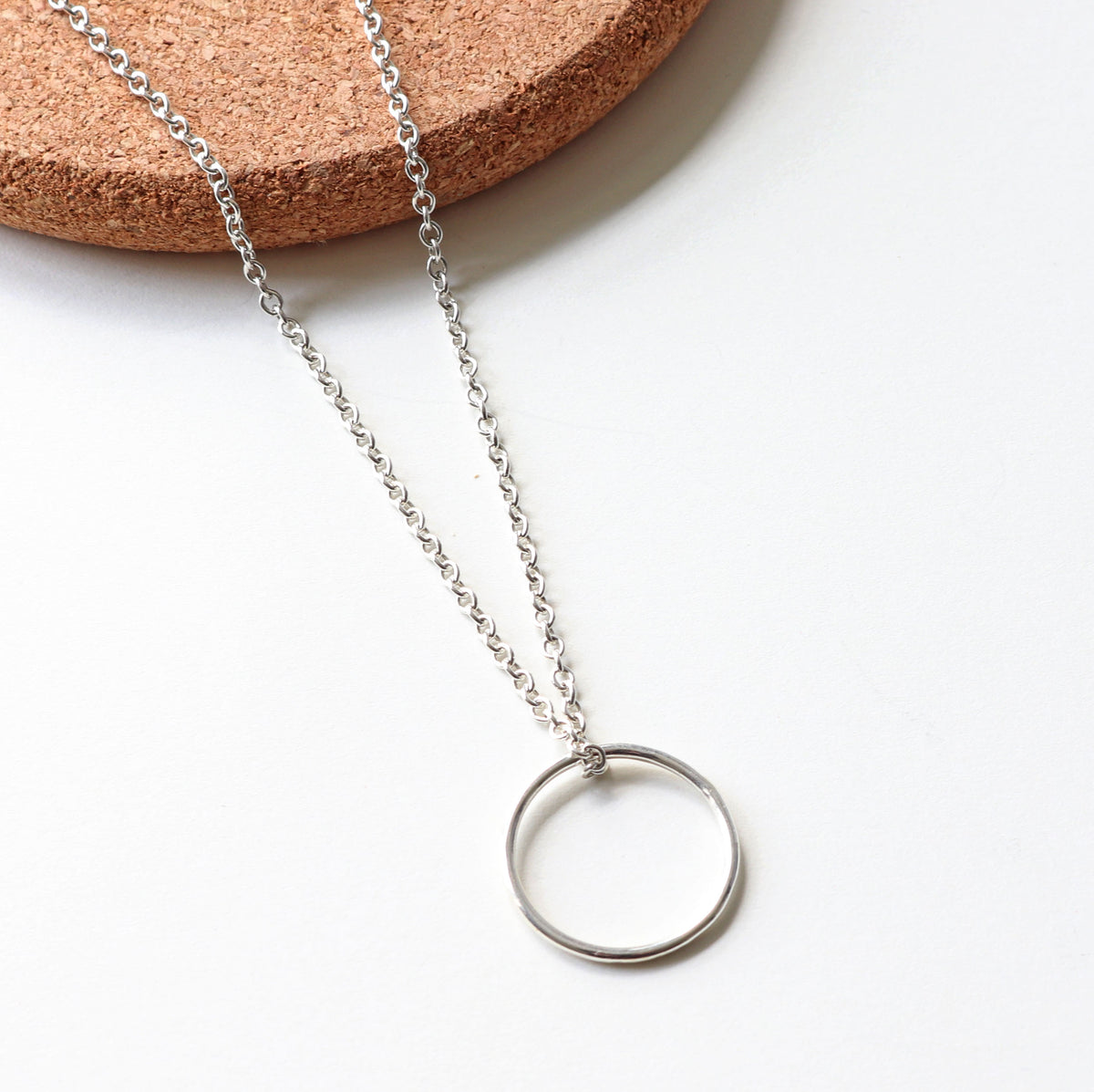 Silver necklace with a circular pendant on a white background