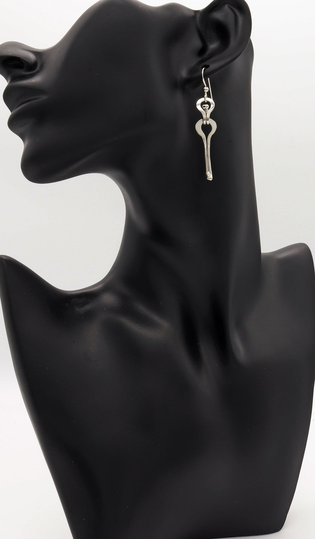 A handmade Argentium solid silver keyhole drop earring displayed on a black female mannequin head and neck bust against a white background.