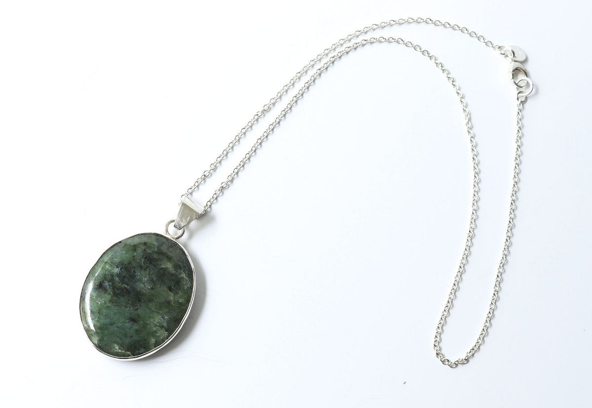 Hand-cut Wyoming nephrite jade oval pendant with Argentium Silver bail and chain shown against a plain white background.