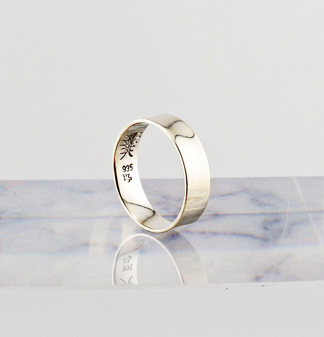 Argentium Silver ring with engraved design on a marble surface
