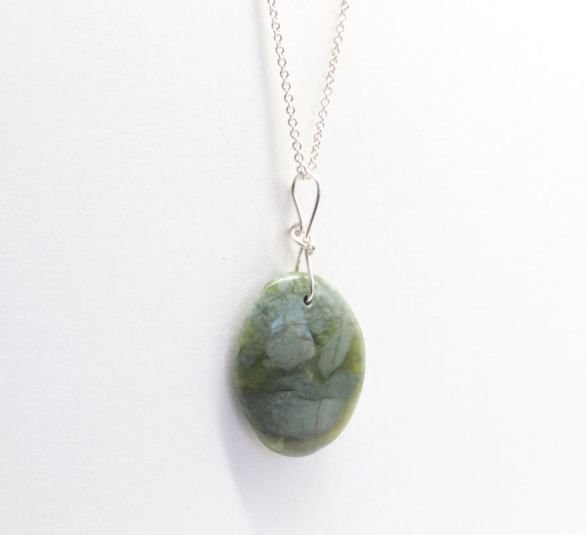 An Argentium silver chain necklace with an oval green stone pendant, photographed against a plain white background.
