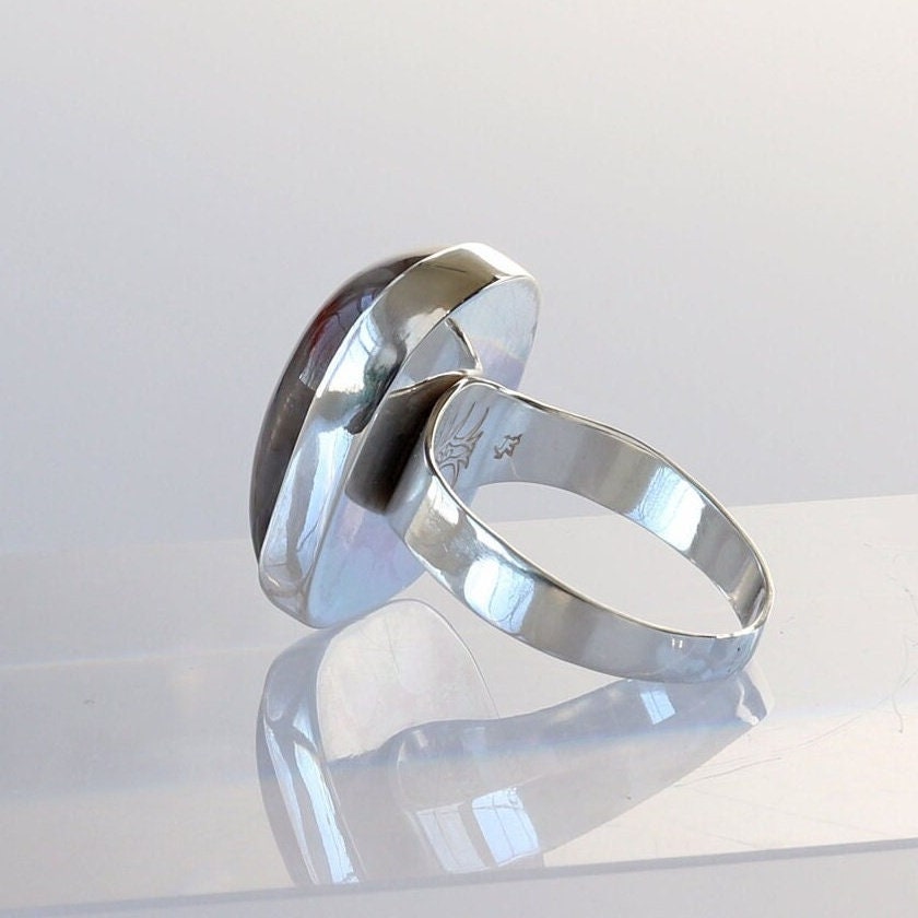 Back view of Petrified Rainbow Wood men's gemstone ring displaying the makers mark.  This gemstone has been handcut and polished in our Missouri studio to showcase the natural red and brown hues and captivating patterns.  Encased in sterling 935 Argentium silver with a fine silver bezel (.999) which work together to create a bold and timeless eye-catching design.  