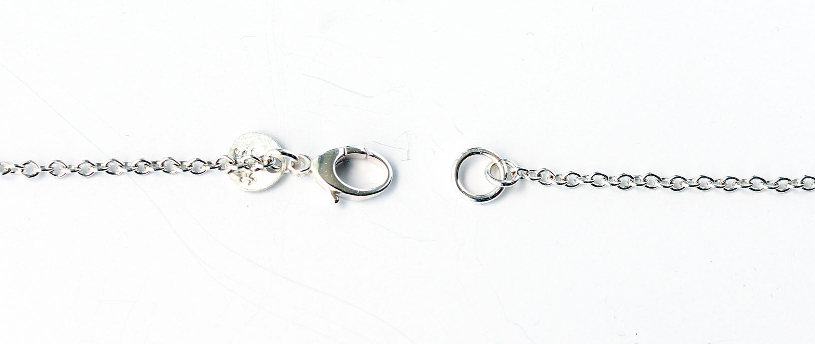 Closeup of sterling silver teardrop lobster clasp on 1.9 Argentium chain necklace on a white background.