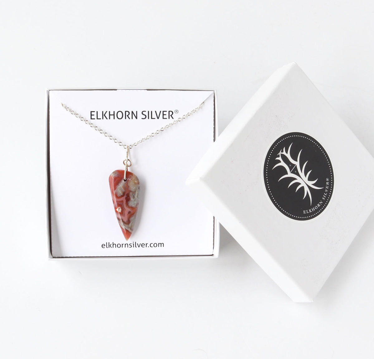 Elkhorn Silver necklace with a Crazy Lace tear-drop shaped  pendant, displayed on its branded white gift box next to the lid on a clean white background.