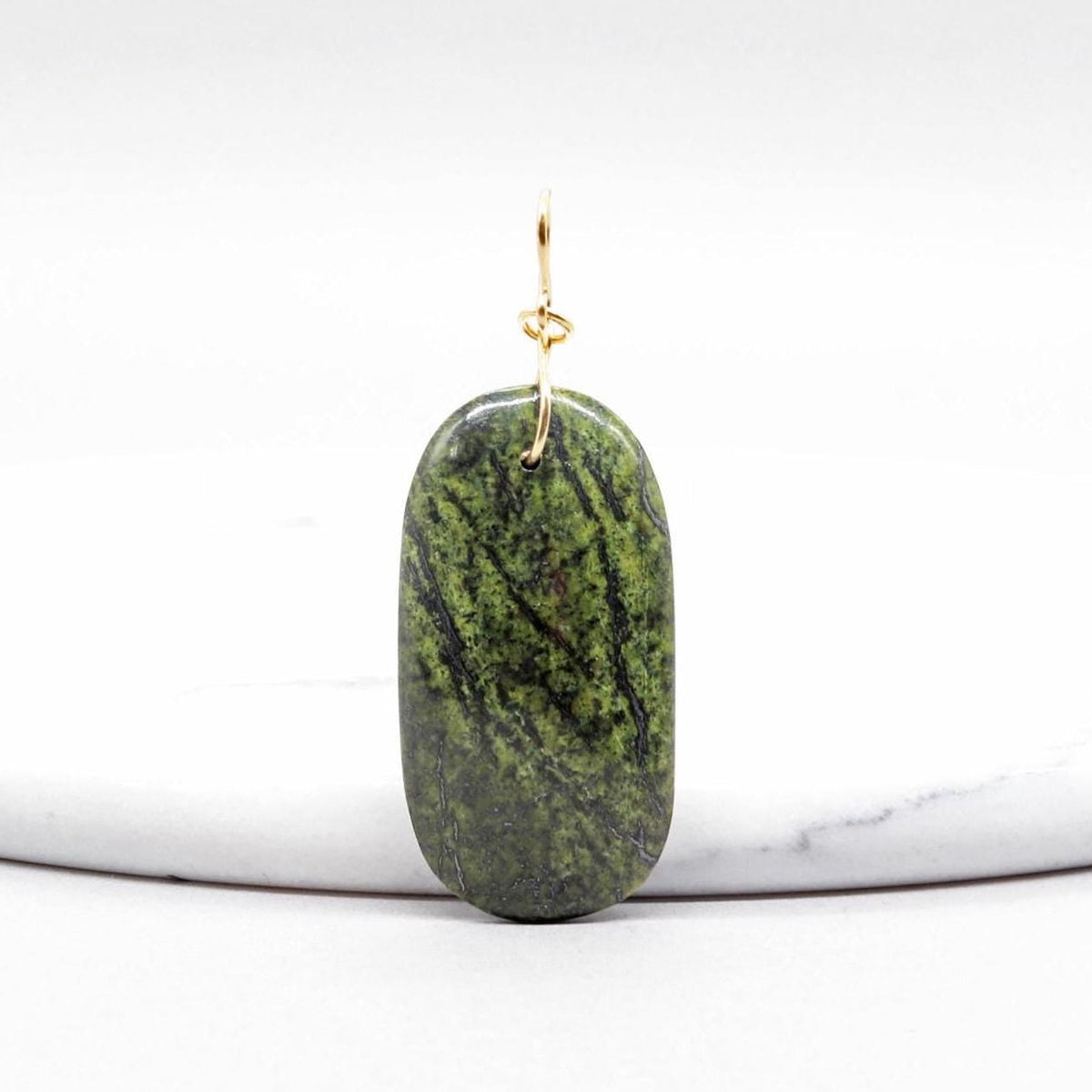 Forest Green Jasper Pendant with Gold Fill shown on white marble slab against white background.