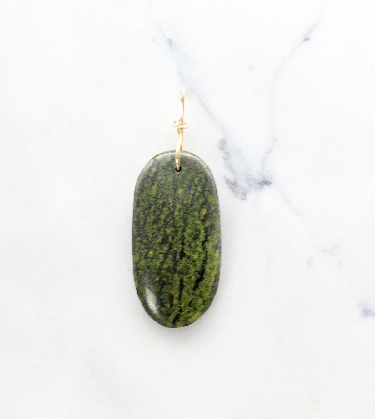 Forest Green Jasper with gold loop on a white marble surface.