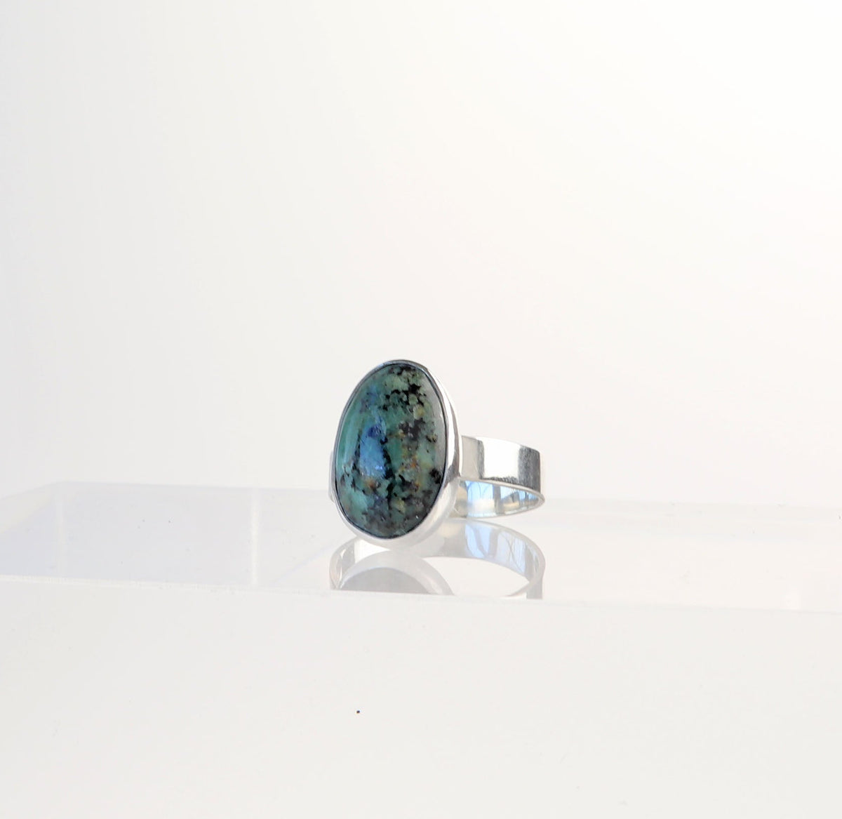 Fraser River Turquoise ring in solid Argentium 935 silver, Size 8 displayed on a white geometric pedestal against a white background.