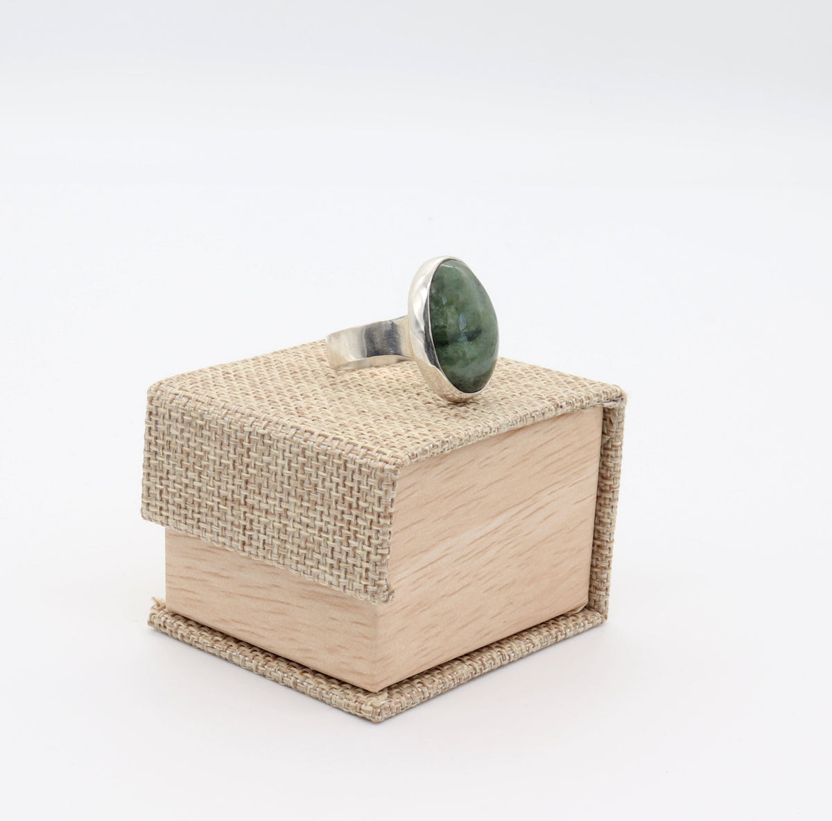 A Natural Wyoming Nephrite Jade ring handcrafted in solid Argentium 935 silver, size 11 1/4, displayed on a small textured beige jewelry box against a white background.
