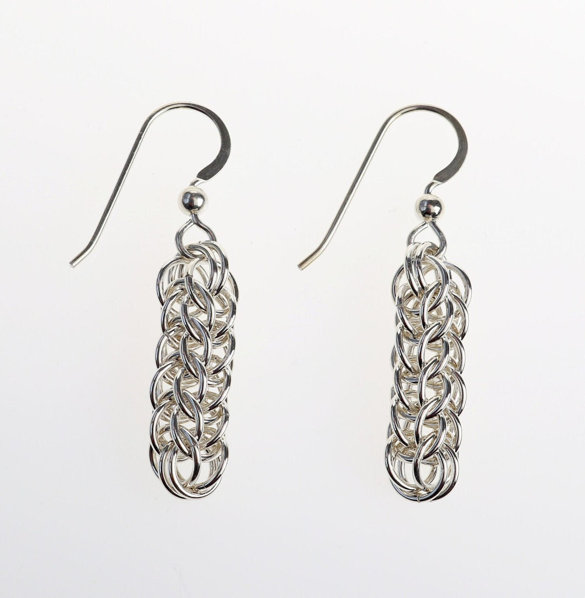Our handcrafted solid silver dangle earrings, showcase a mesmerizing full Persian weave pattern, featuring interlocking links that create a captivating visual effect in premium sterling 935 Argentium® silver. The 935 Argentium® Silver ear wires, add a touch of elegance, ensure a comfortable and secure fit and are hypoallergenic.  Shown on white background.