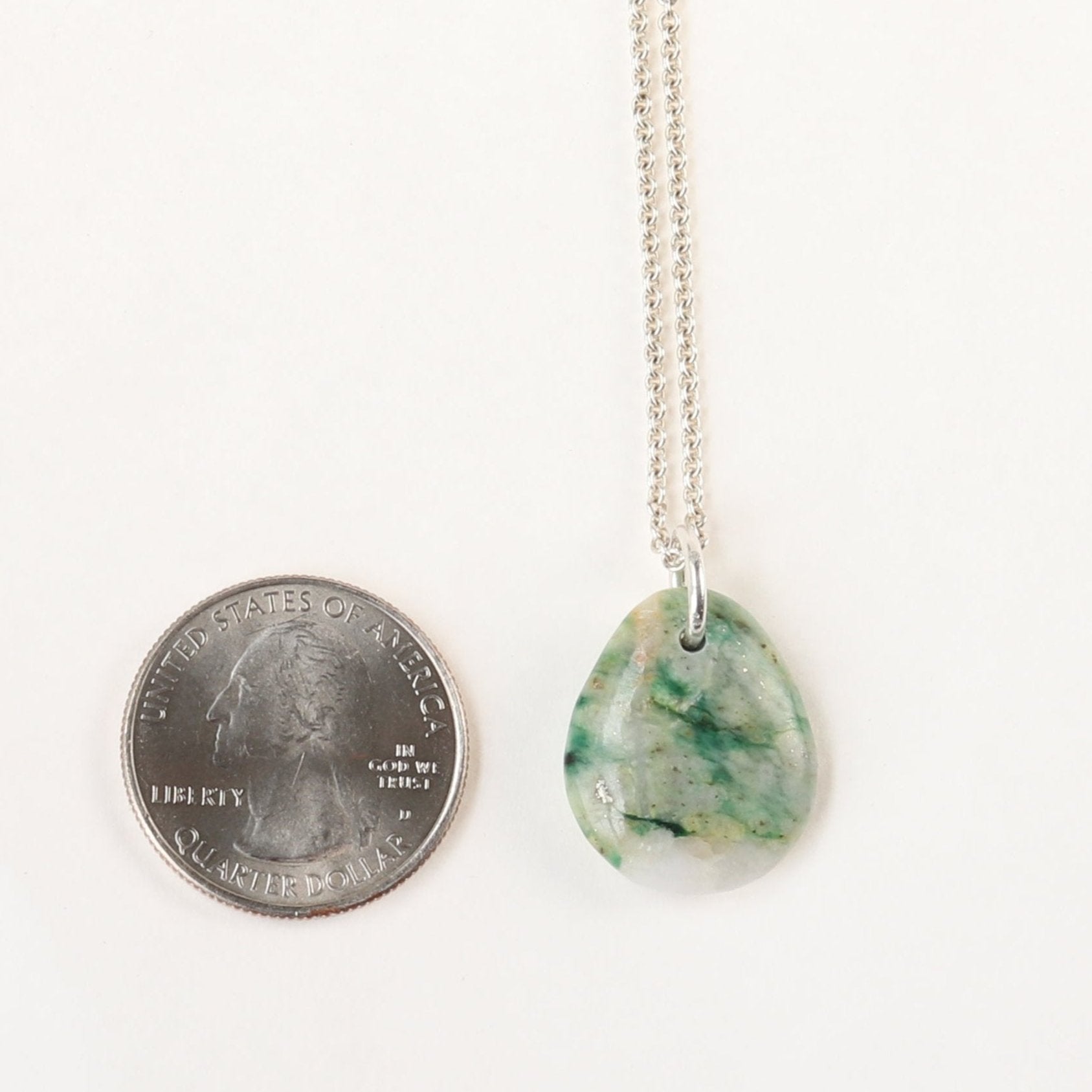 A stunning 24.68 mm Mariposite gemstone pendant, handcrafted in Missouri, USA.  This unique piece features a teardrop shape, handcut and polished on both sides to showcase the natural green and white hues of the Mariposite stone. The pendant is complemented by a custom 940 Argentium silver bail, adding a touch of sophistication to the design. To make this piece ready to wear, an optional matching 1.7 Argentium silver chain is offered.