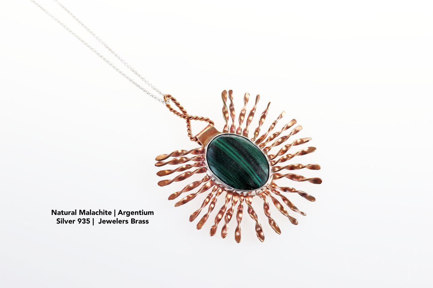 Natural Malachite gemstone set in Argentium Silver surrounded by a Jewelers brass starburst pattern pendant. Text Overlay reads Natural Malachite | Argentium Silver 935 |  Jewelers Brass