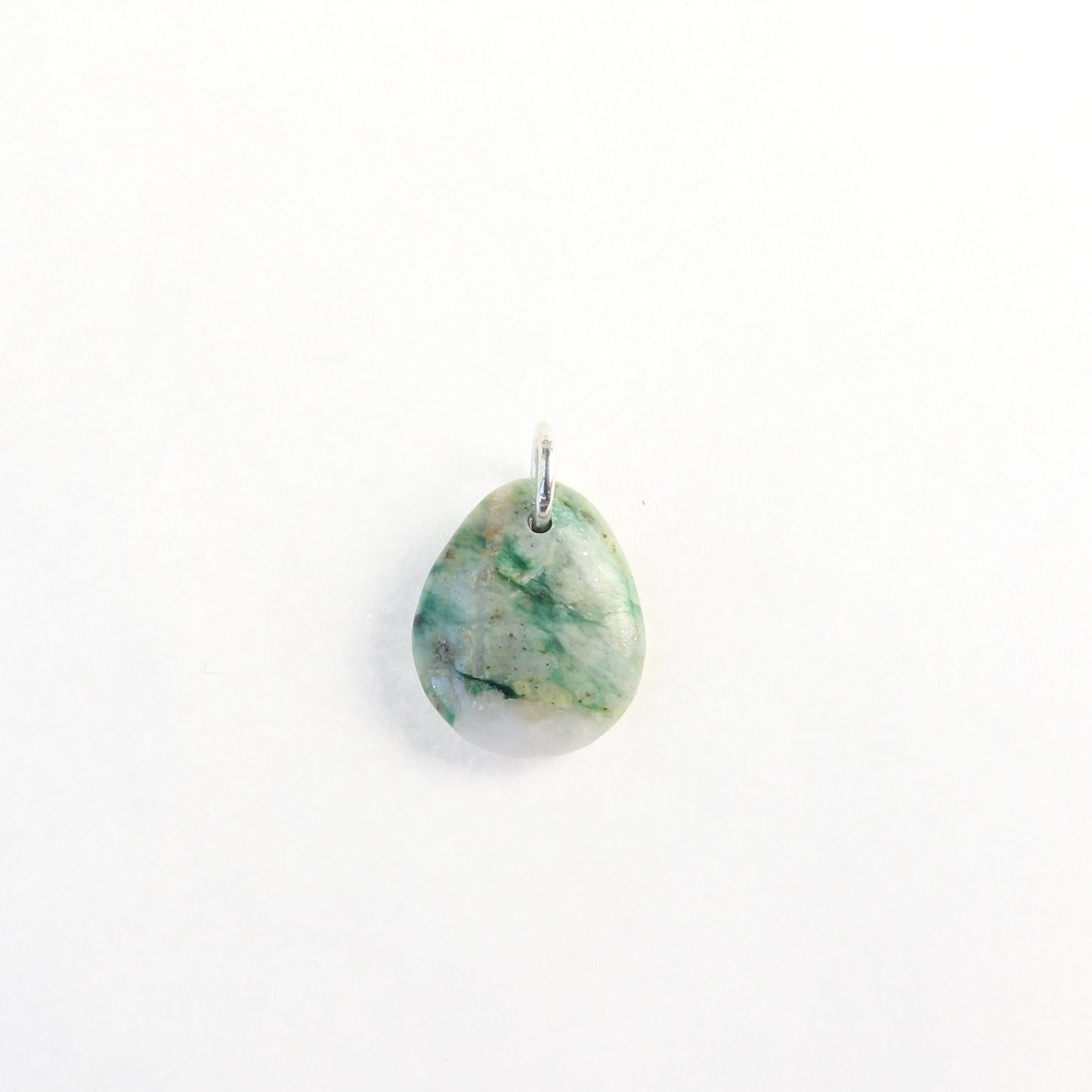 A stunning Mariposite gemstone pendant, handcrafted in Missouri, USA. This unique piece features a teardrop shape, handcut and polished on both sides to showcase the natural green and white hues of the Mariposite stone. The pendant is complemented by a custom 940 Argentium silver bail, adding a touch of sophistication to the design. 