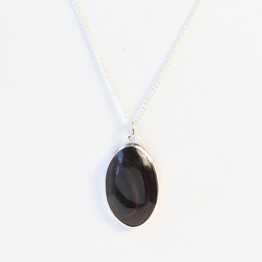 A Mahogany Obsidian pendant displays swirling deep reddish-brown and dark mahogany hues, set in  Argentium® 935 Silver shown on white background with silver necklace.