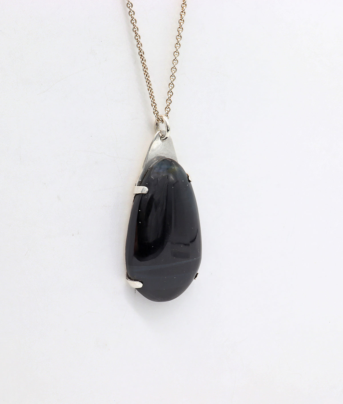 Handcrafted African Blue Tiger's Eye teardrop pendant with deep blue-black reflective gemstone, solid Argentium 935 silver tabbed setting and silver chain.  Show on white background.