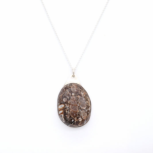 This 1.87 inch Turritella Agate pendant has been handcut and polished in our Missouri USA studio to showcase the intricate patterns of these perfectly preserved fossilized snails originating from the Green River Formation of Wyoming. It's elegantly encased within a solid, oval flat-back bezel made of sterling Argentium® 935 Silver.