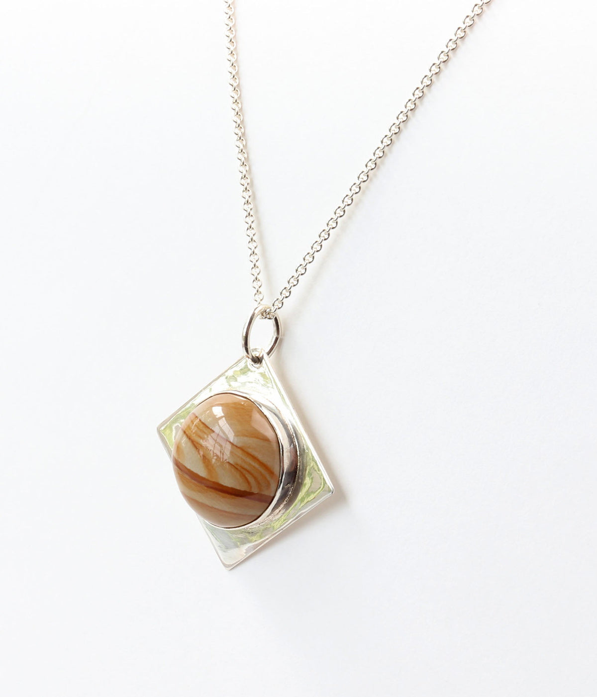 A natural Picture Jasper cabochon, hand-cut and polished to showcase its warm cream, tan, rust, and brown landscape-like banding in solid Argentium Silver. Shown on white background.