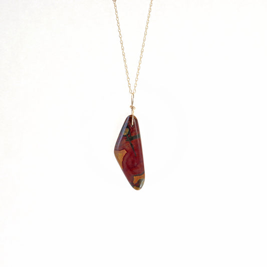 A natural, one-of-a-kind Poppy Jasper pendant, hand-cut and freeform polished on both sides to reveal the mesmerizing deep red, yellow, and green patterns inherent in the stone. The custom 14/20 Gold Filled infinity bow-shaped bail, paired with a complementary double-rope necklace in 14/20 Gold Fill, completes the look. Versatile and stylish, this piece is perfect for any occasion.