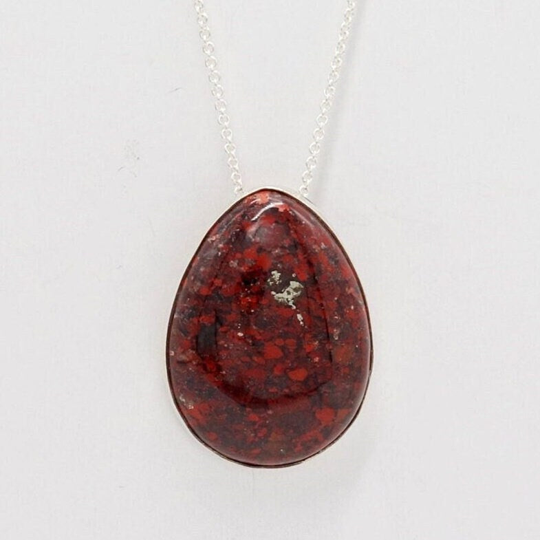 Natural Brecciated Jasper teardrop pendant with deep red, brown and gray patterning on an Argentium® 935 Silver chain against a light gray background.
