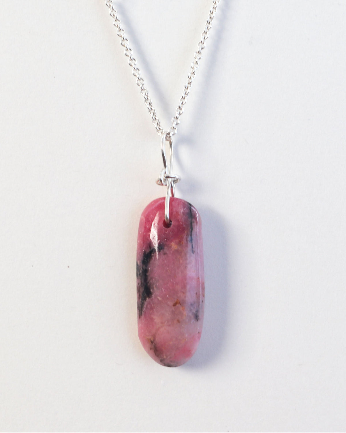 Natural Rhodonite pendant necklace with pink and black stone on 1.7 mm Argentium Silver chain shown on light gray background