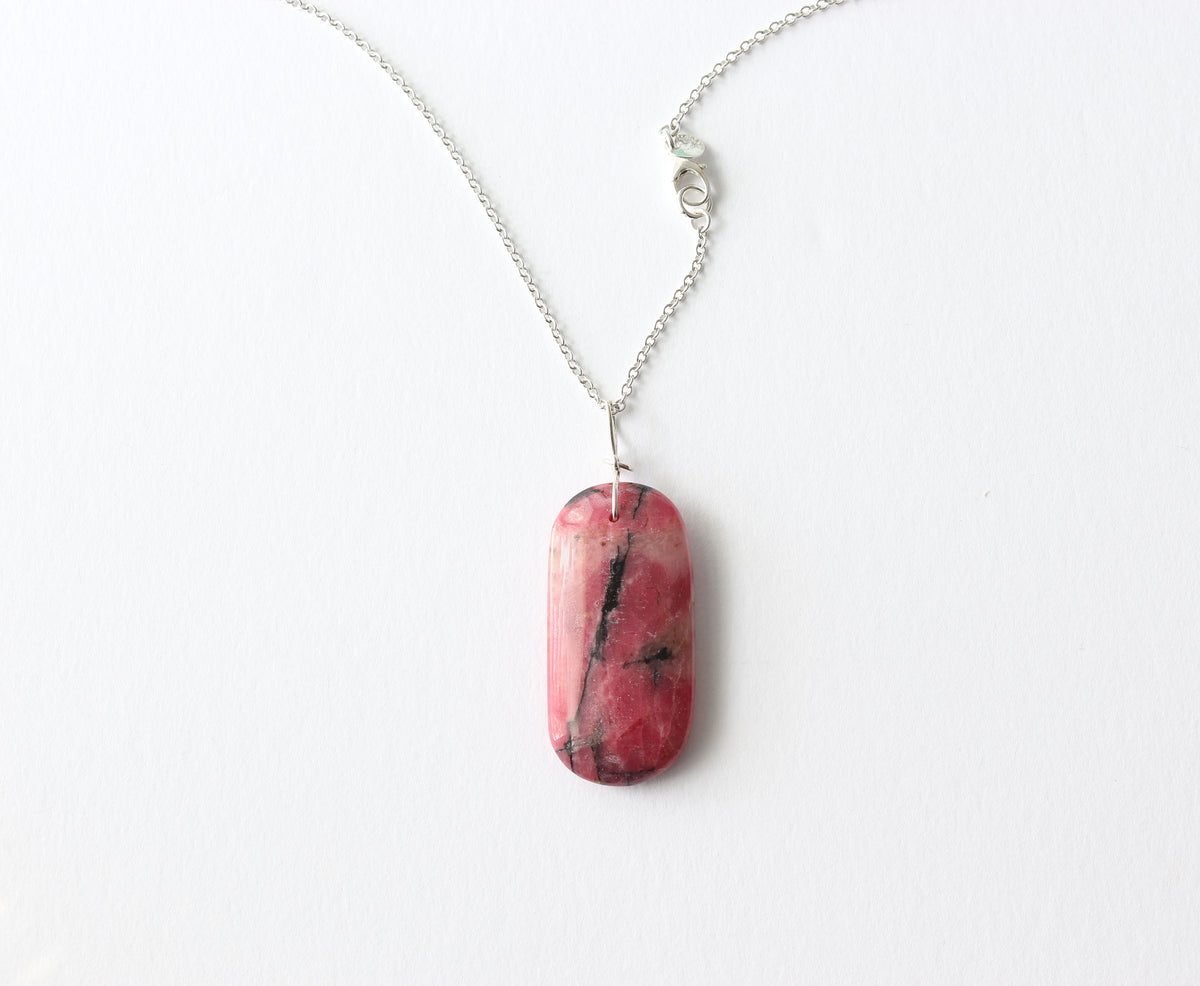 An Argentium silver chain necklace with a polished pink Rhodonite pendant featuring black veining, displayed on a clean white background.