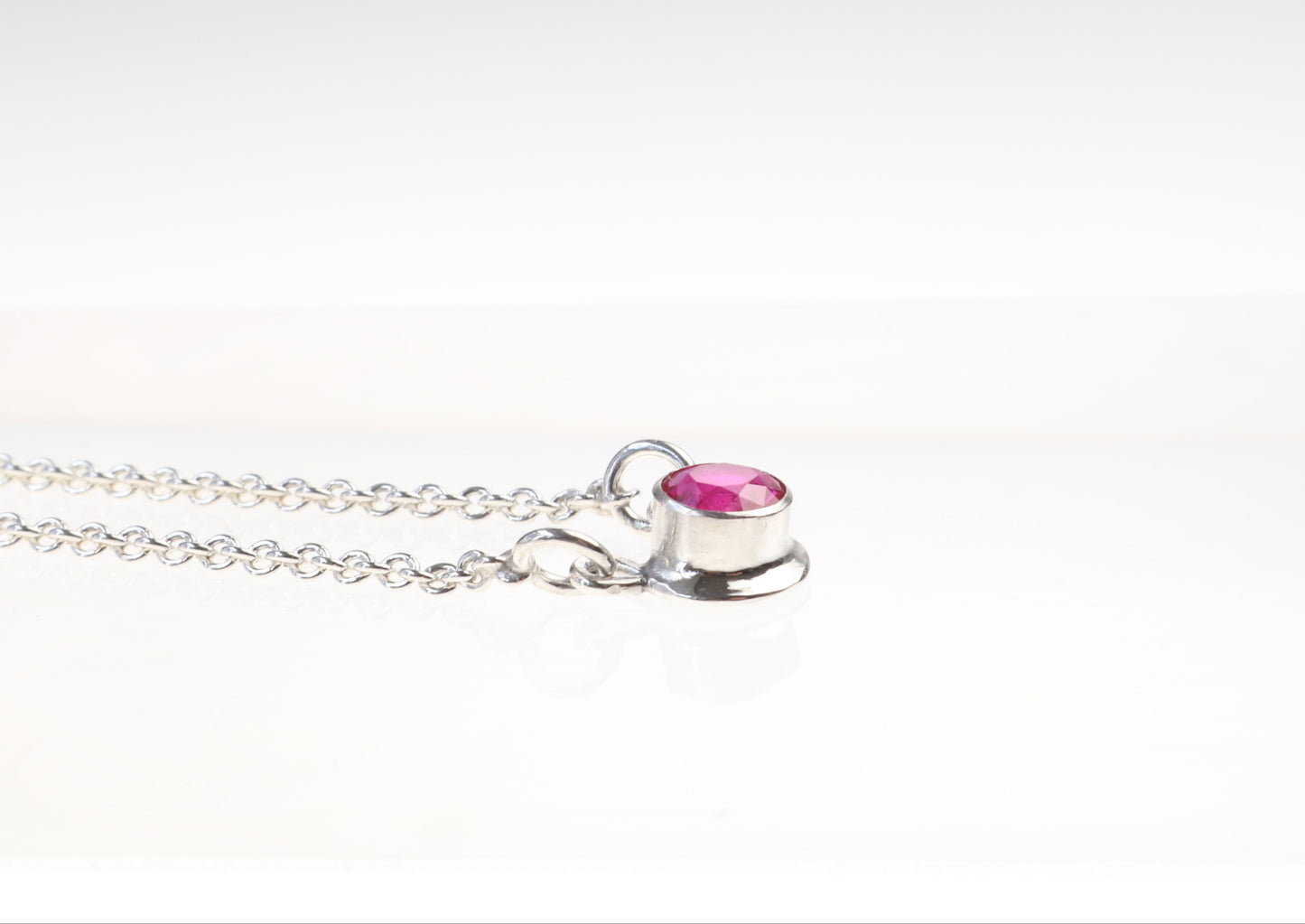 Argentium Silver necklace with a lab ruby gemstone pendant on a white background