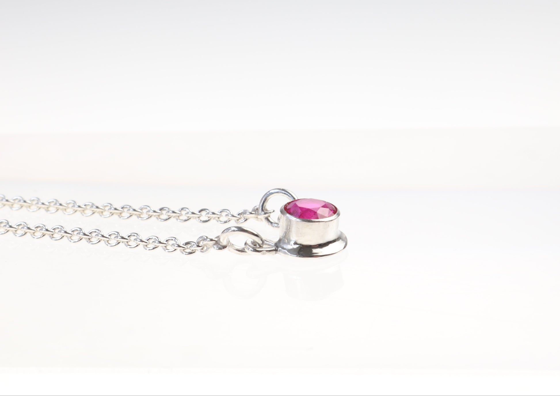 Argentium Silver necklace with a lab ruby gemstone pendant on a white background