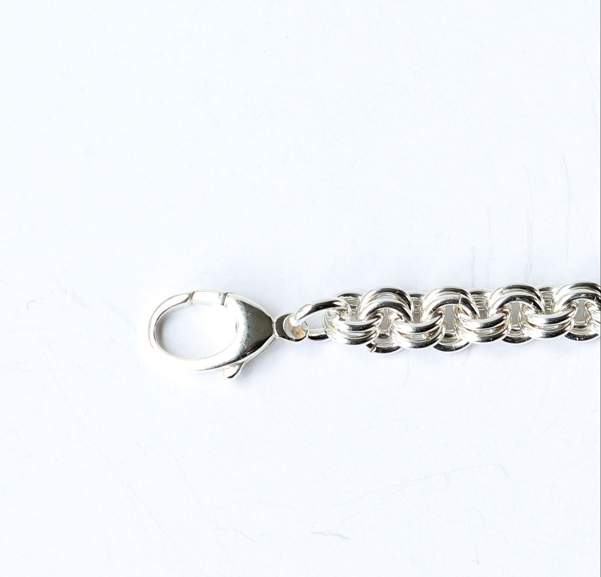 A closeup of the Sterling Silver teardrop clasp and double cable chain bracelet on a white background