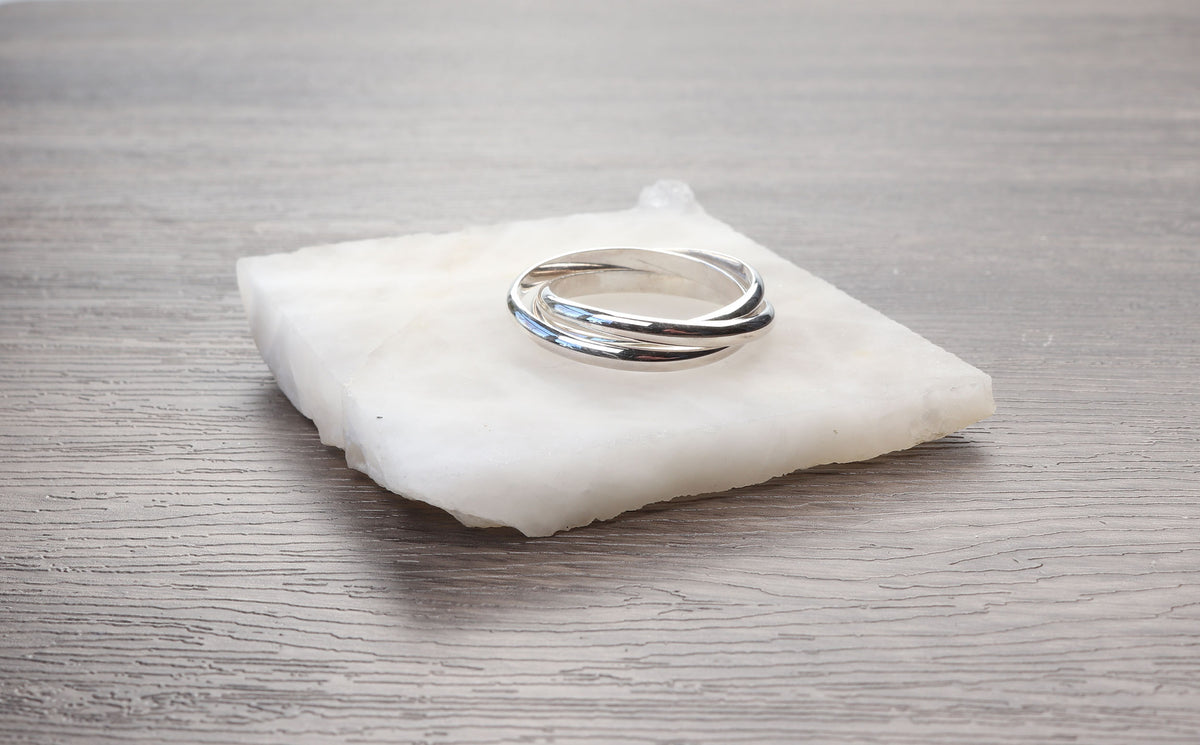 Handcrafted solid sterling silver rolling ring with three interlocking polished bands on white cushion