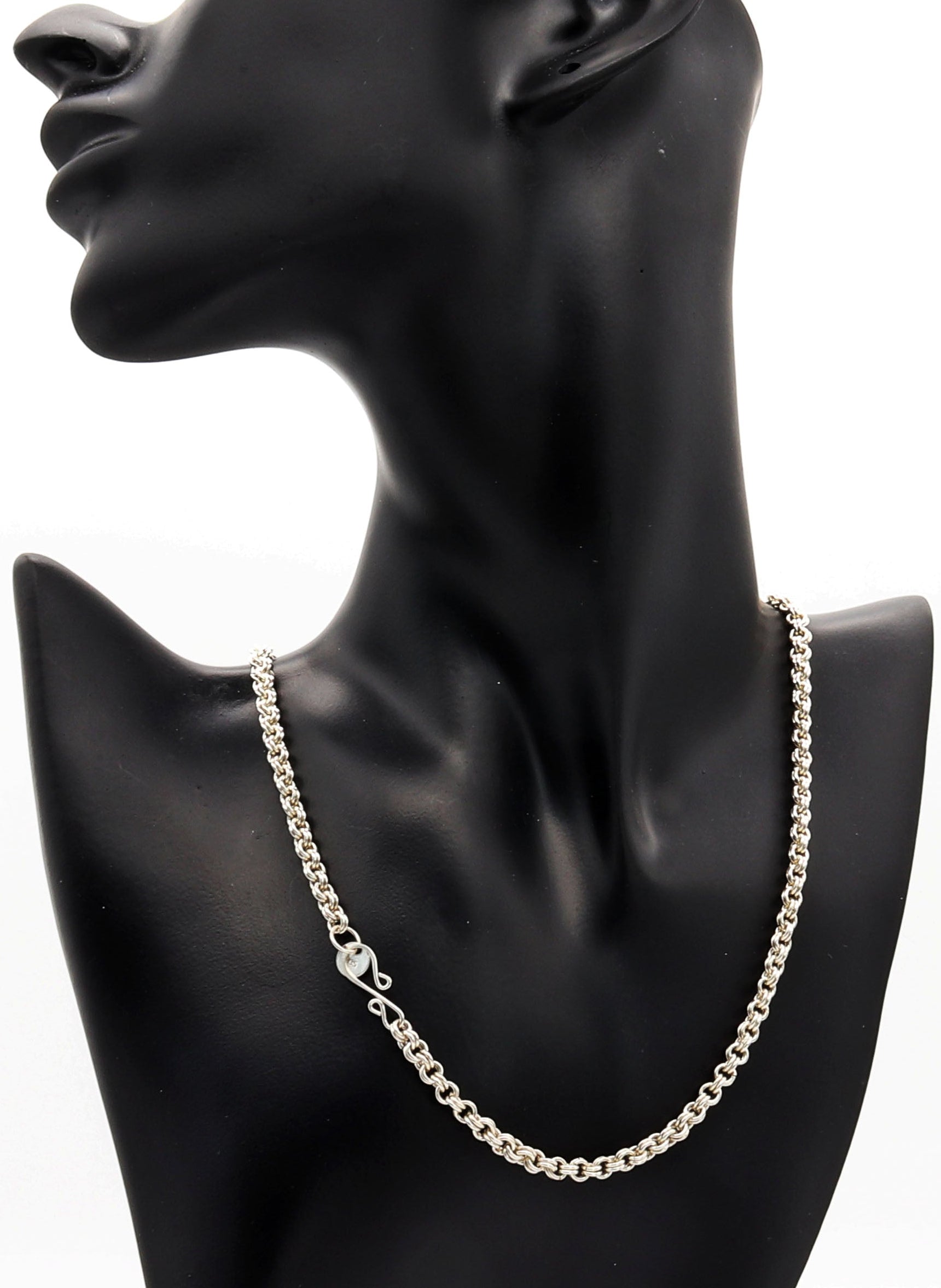 Silver chain necklace on a black mannequin bust against a white background