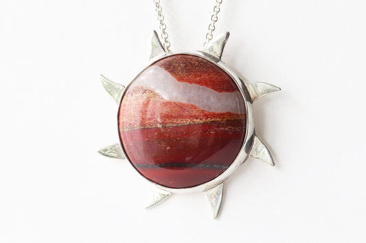 Closeup of Snakeskin Jasper pendant, hand-cut and polished to showcase its vibrant flaming red, rich brown, and creamy natural patterns. Encased in premium Argentium® 935 silver