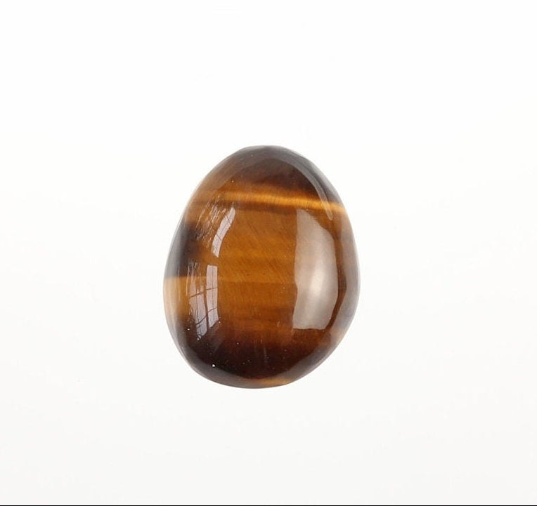 Front view of hand-cut natural Tiger's Eye cabochon showing golden-brown banding and chatoyancy on a white background.