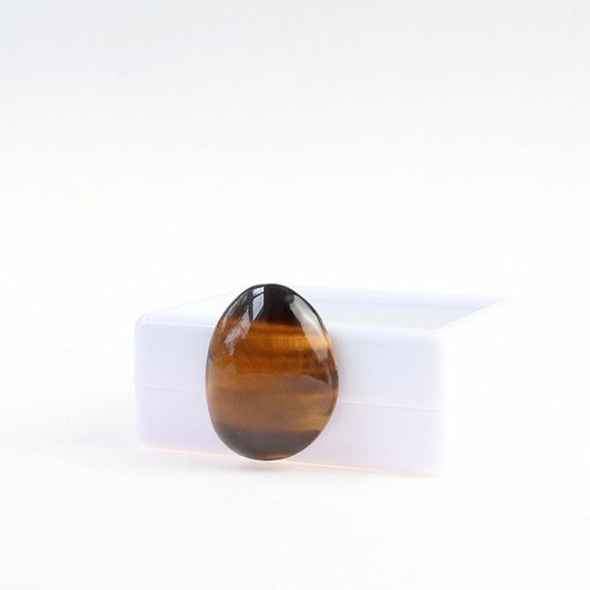 Hand-cut natural Tiger's Eye cabochon with golden-brown banding and chatoyancy, displayed against a white gem box.