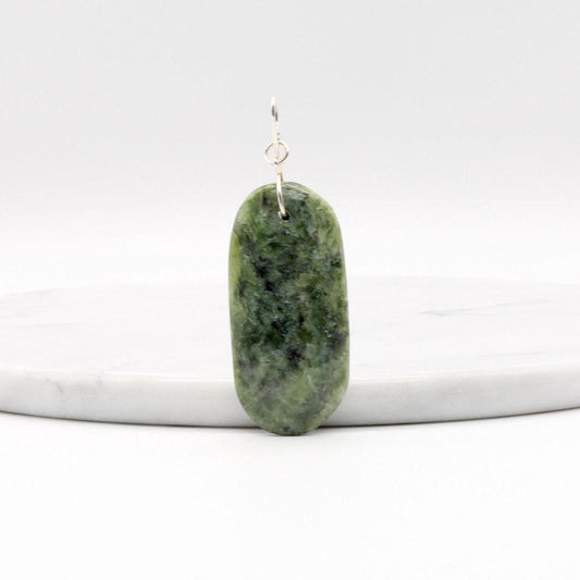 Wyoming Jade Pendant with Argentium Silver Custom bow shaped bail shown leaning on a whiite marble slab against a white background.