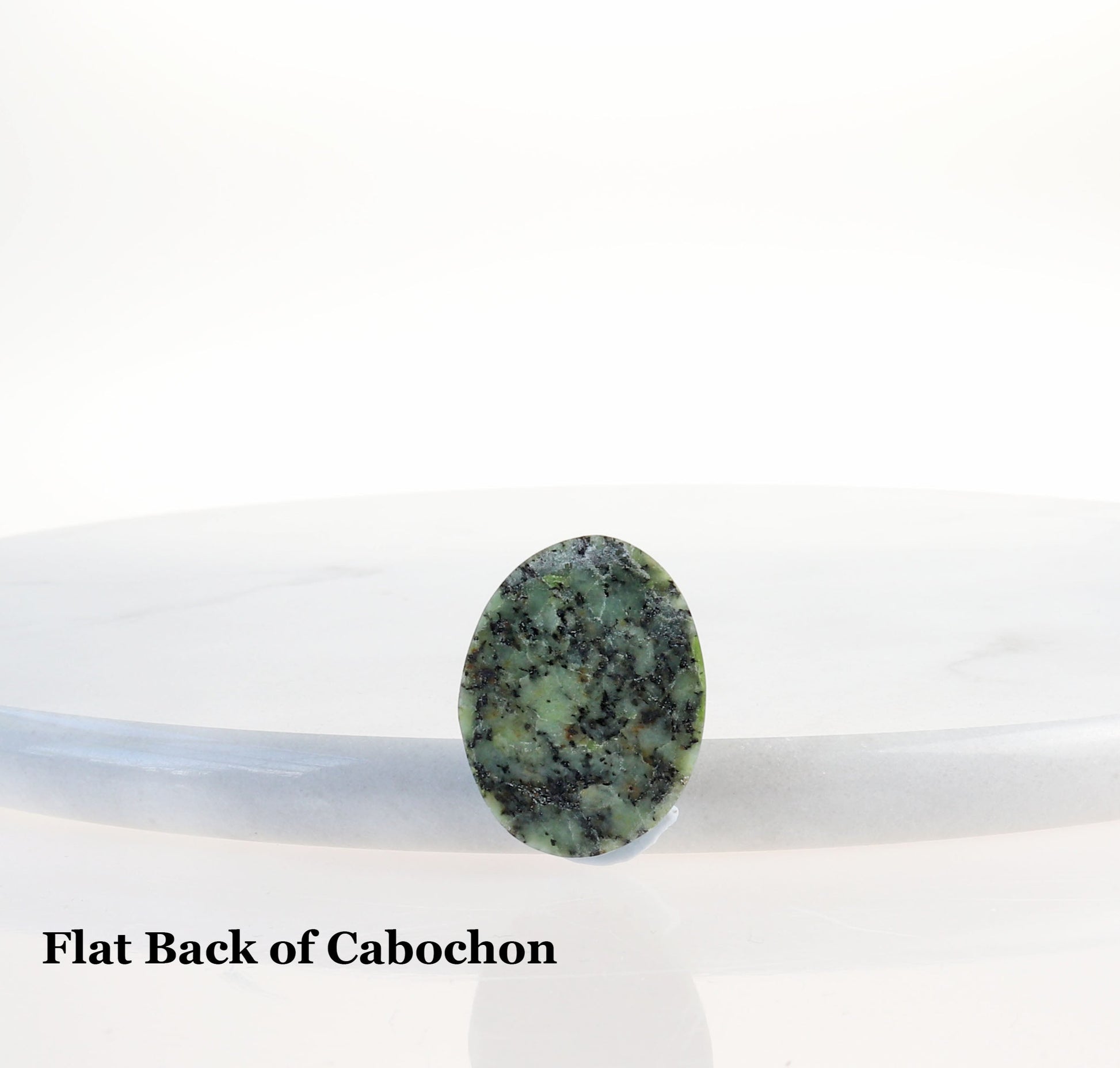Flat back of handcut polished Fraser River Turquoise Cab shown against white marble.