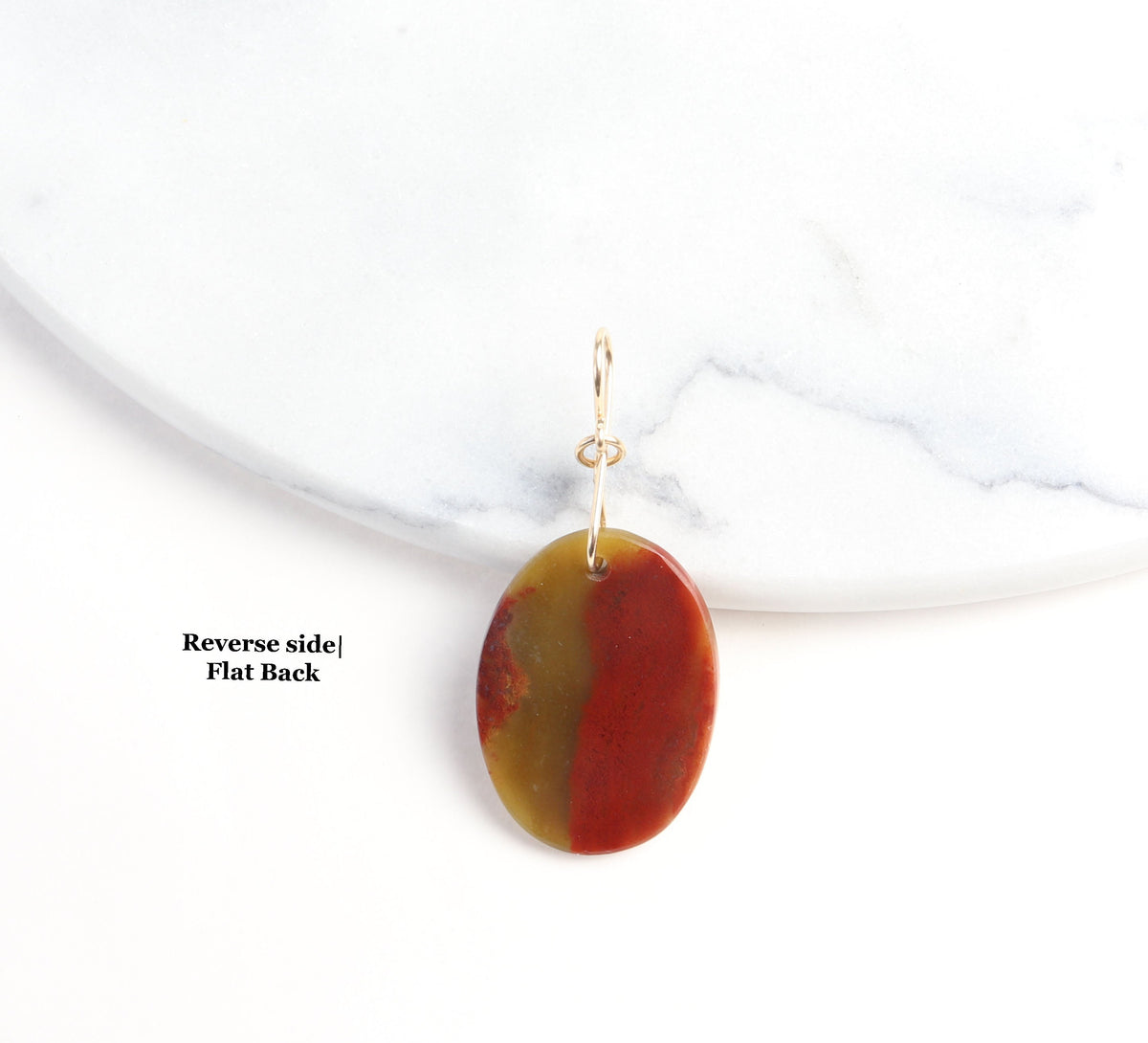 Shown against a white marble slab is this sonoran sunrise pendant cabochon with flat back.  Shown on white background.