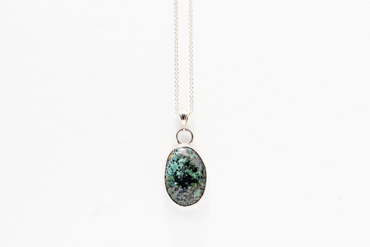 Fraser River Turquoise featuring blue green and black patterns showcased in Argentium Silver and fine silver setting. pendant on a white background
