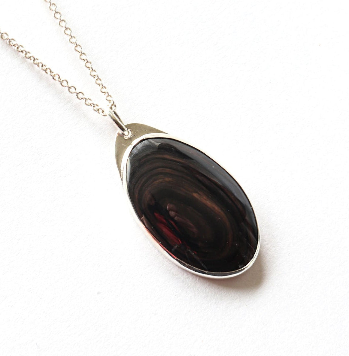 A Mahogany Obsidian pendant with swirling patterns in deep reddish-brown and dark mahogany hues,  set in Argentium® 935 Silver.