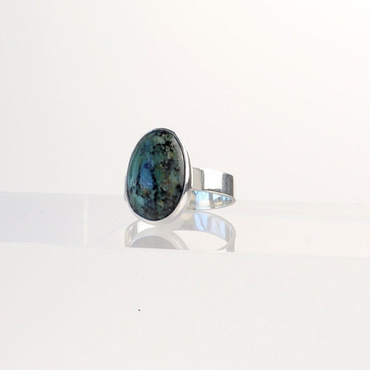 A Fraser River Turquoise ring features a handcut and polished gemstone with stunning blue-green hues and bold black mottled matrix, echoing the rugged landscape of the Fraser River region in British Columbia.