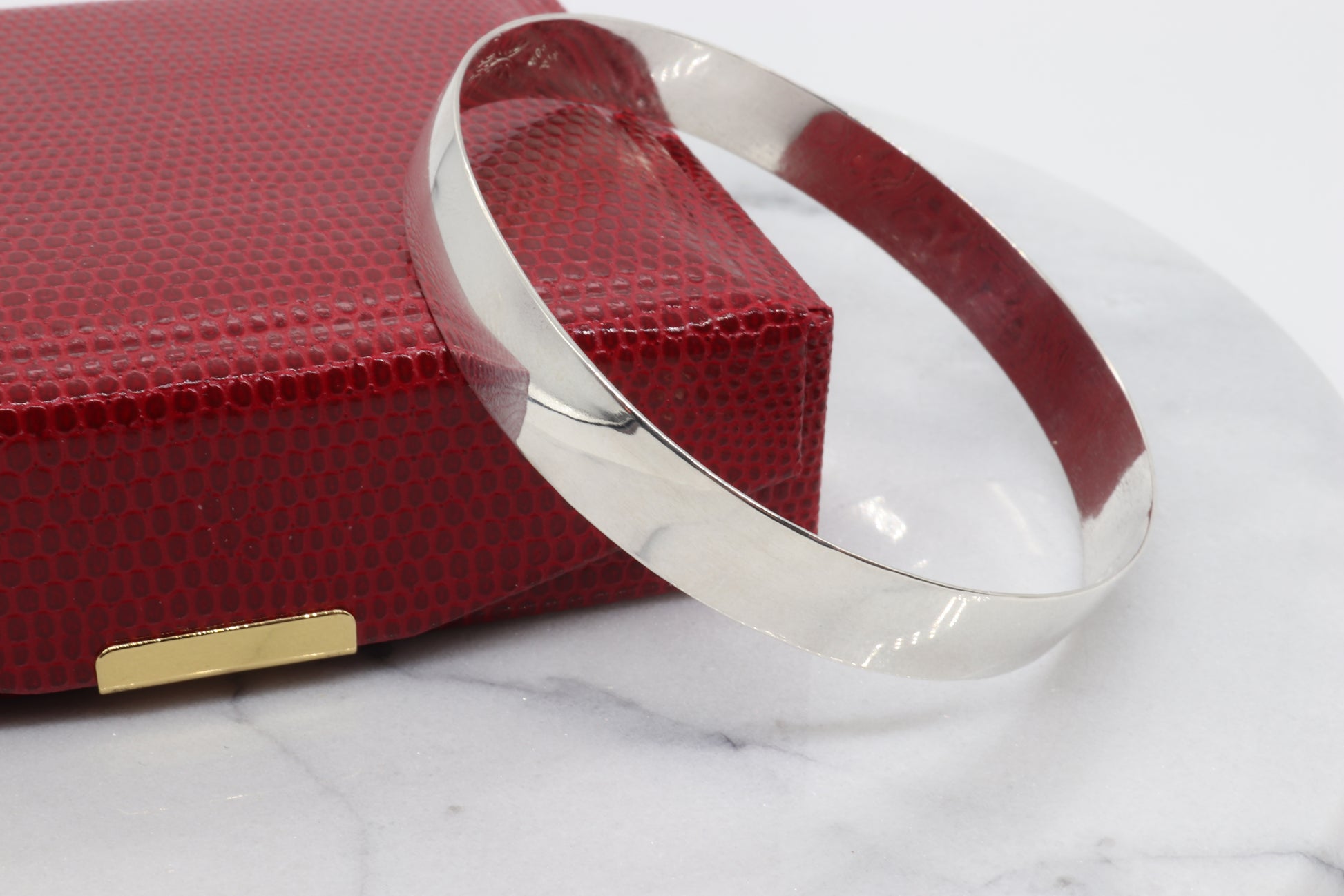 9mm Bangle Bracelet, Crafted from 935 Argentium Silver, Features a Subtle Beveled Design shown next to red gift box.