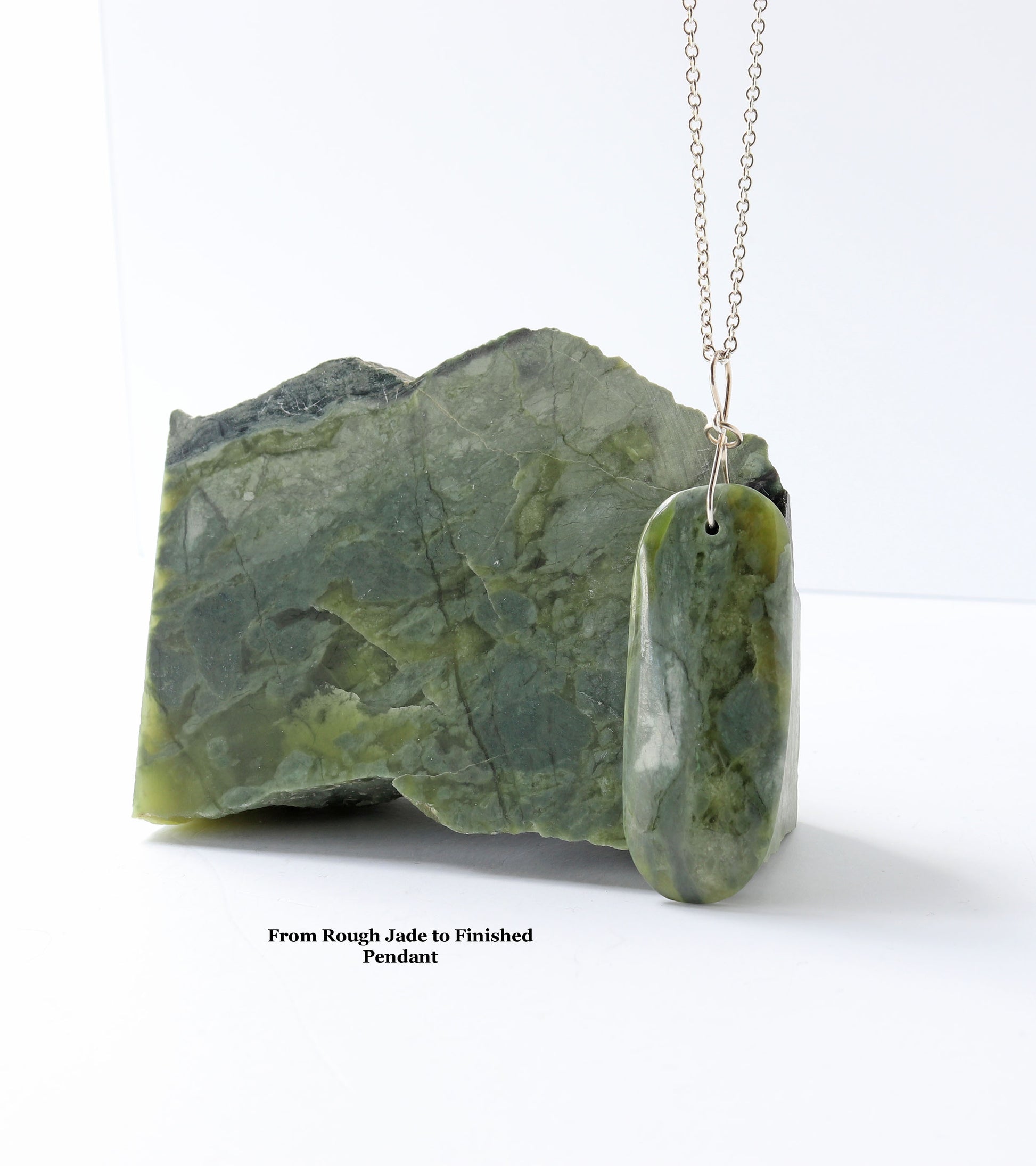 A polished green jade pendant necklace displayed next to a rough, uncut piece of the same green jade on a white background, with a caption reading 'From Rough Jade to Finished Pendant'.