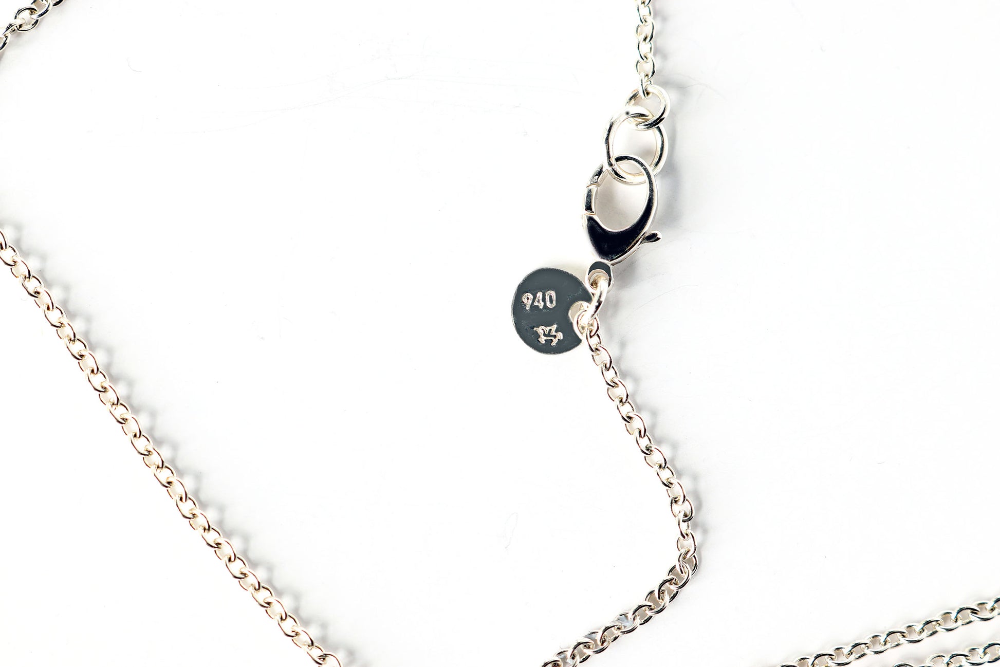 Argentium Silver necklace with the Argentium Winged Unicorn® hallmark tag with 940 — attached to a oval chain necklace with sterling silver .925 teardrop clasp on a white background