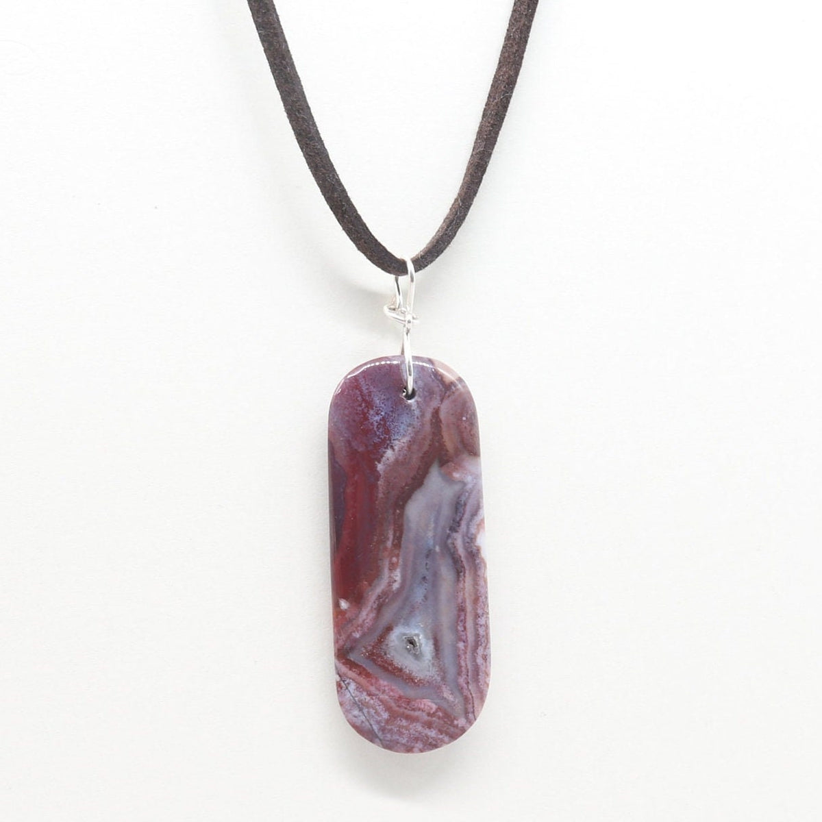 Red Mexican Agate pendant with small crystal feature and translucent patterns shown suspended from black leather cord against white background.
