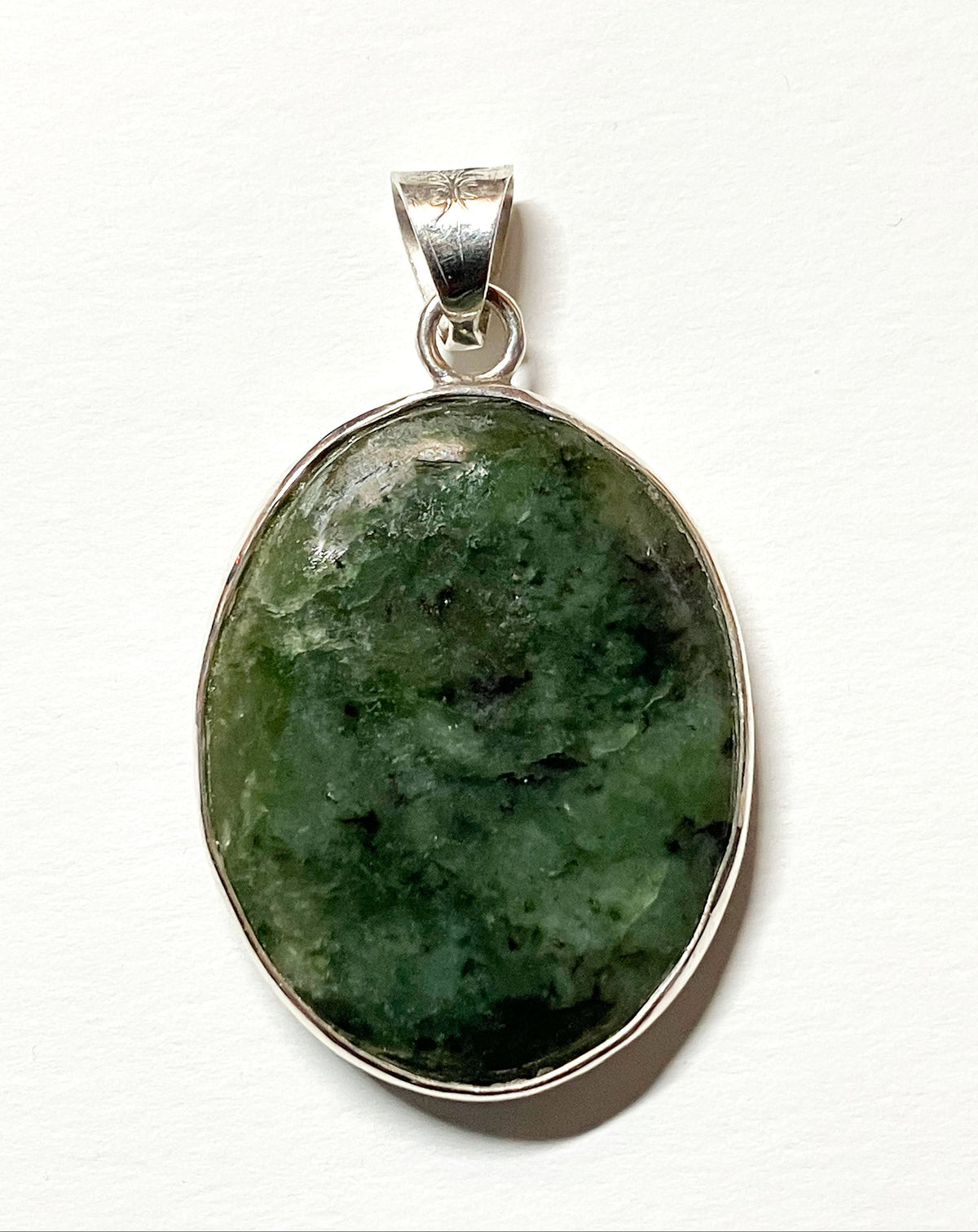Hand-cut Wyoming nephrite jade oval pendant with Argentium Silver bail, shown against a plain white background.