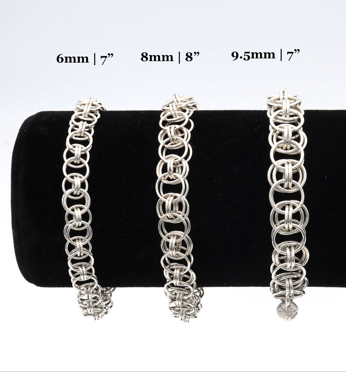 Three silver chain link bracelets displayed on a black velvet jewelry stand against a white background, with size labels above reading 6mm | 7", 8mm | 8", and 9.5mm | 7".