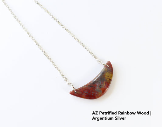 Handcrafted Crescent Shaped AZ Petrified Rainbow wood pendant with attached 935 Argentium Silver chain with S-hook clasp; shown against white background.  Text Overlay AZ Petrified Rainbow Wood Argentium Silver.