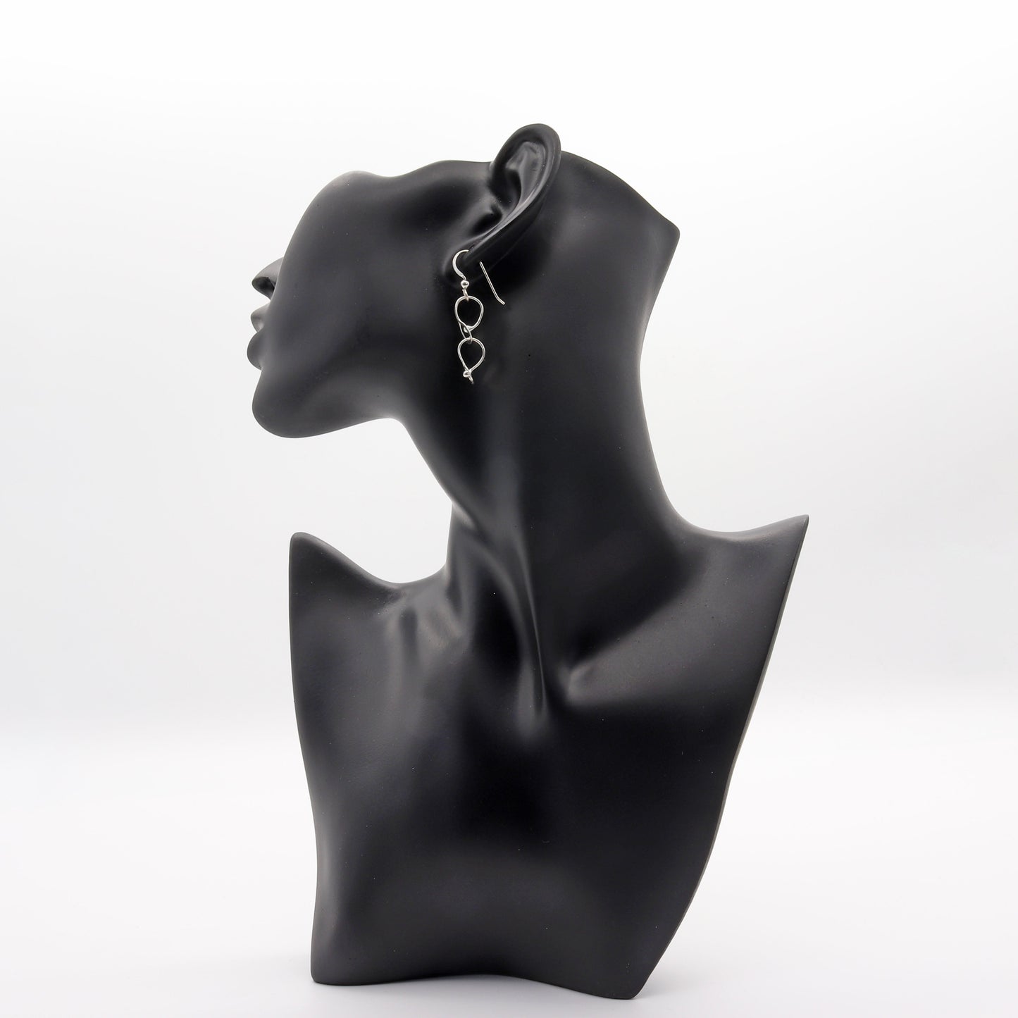 Double loop dangle earrings handcrafted in Argentium® 940 silver, featuring two twisted open loops linked vertically. Displayed on black resin jewelry mannequin.
