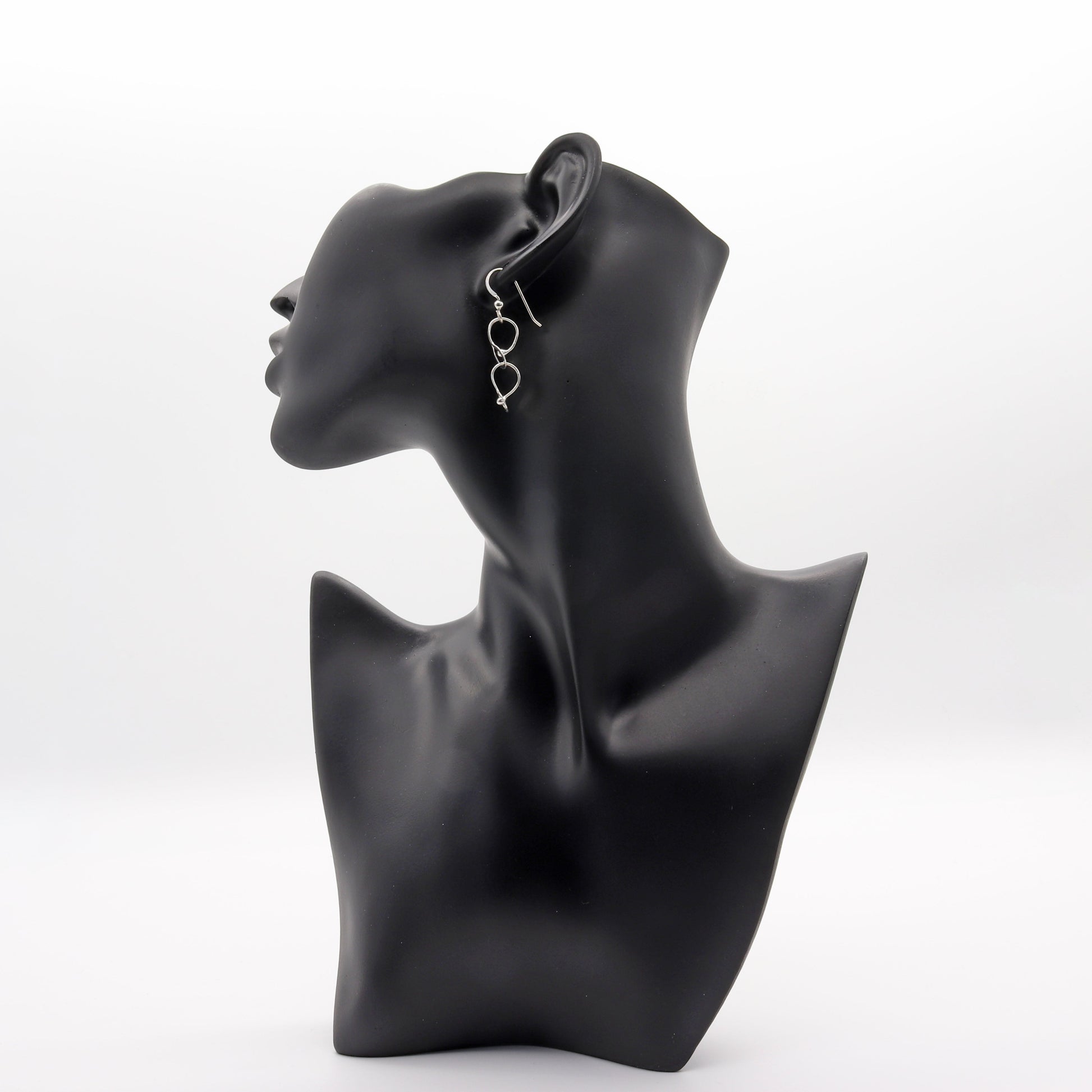 Double loop dangle earrings handcrafted in Argentium® 940 silver, featuring two twisted open loops linked vertically. Displayed on black resin jewelry mannequin.